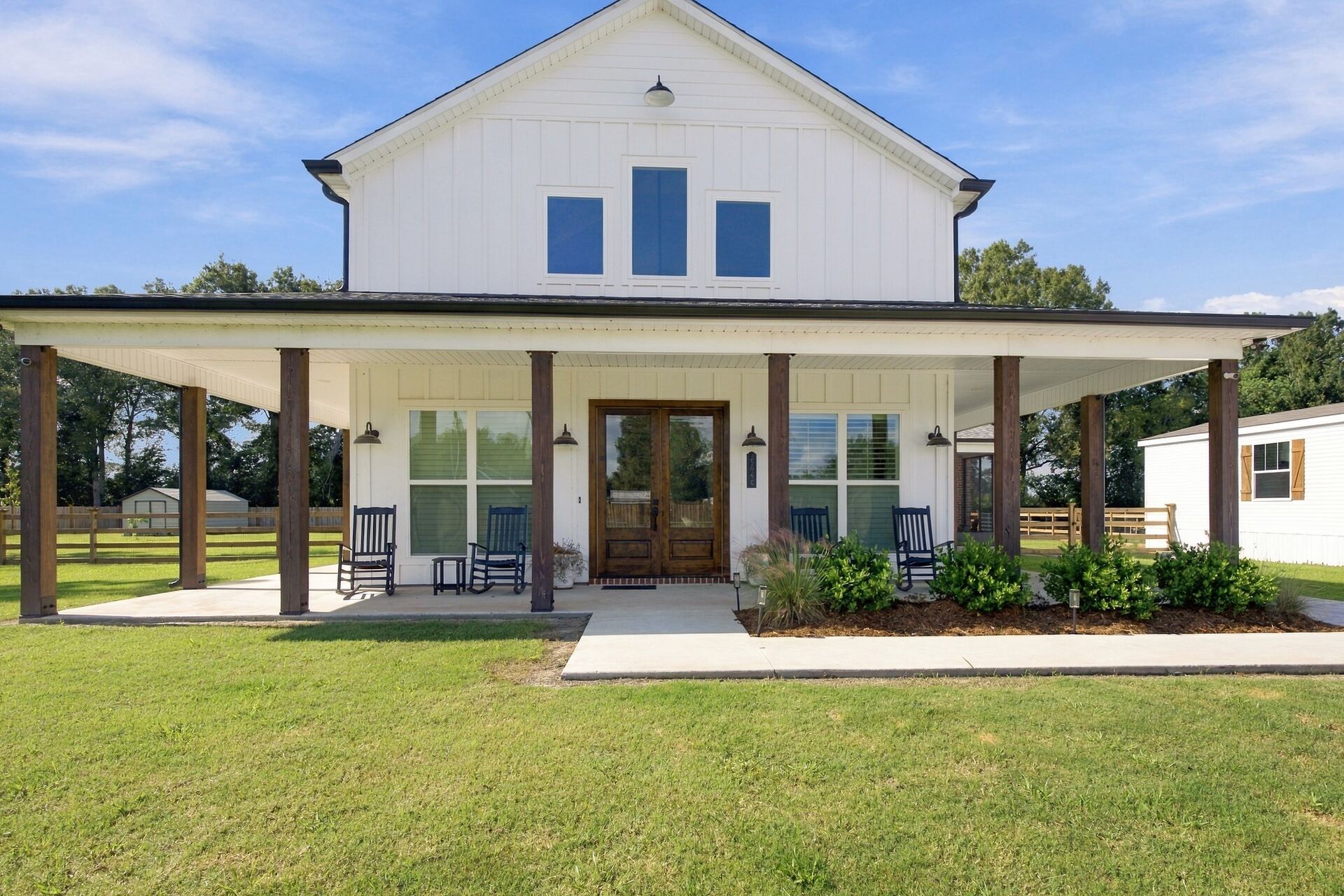 Front elevation of a white board-and-batten farmhouse with a wraparound porch