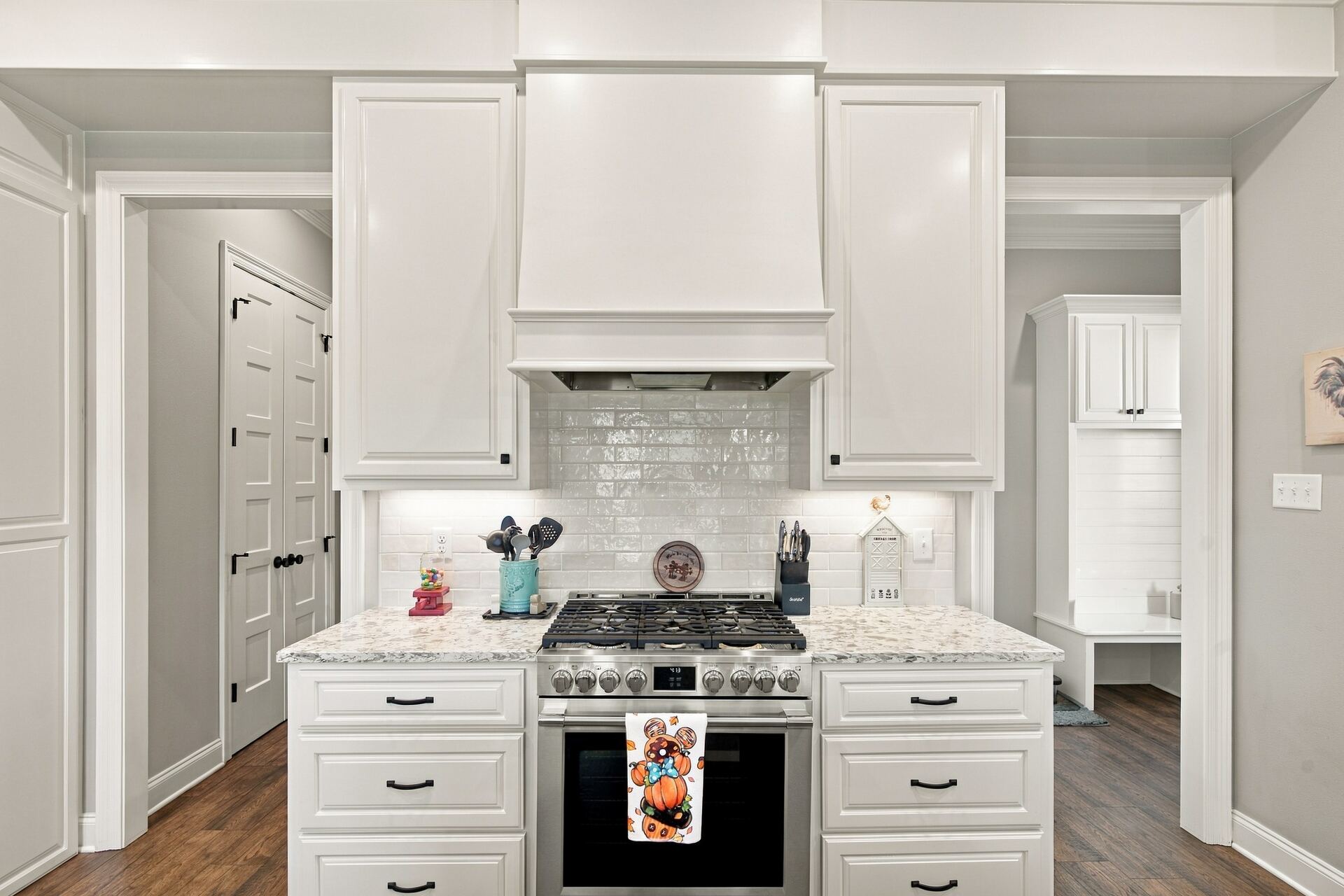 White kitchen cabinetry with a gas range and custom vent hood